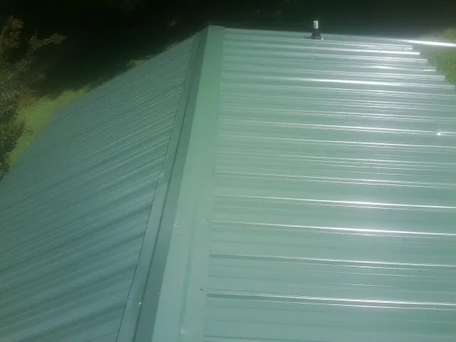 New green metal panels meeting at the ridge of a roof — Flat Roof Repair work by our crew in Spring Gap