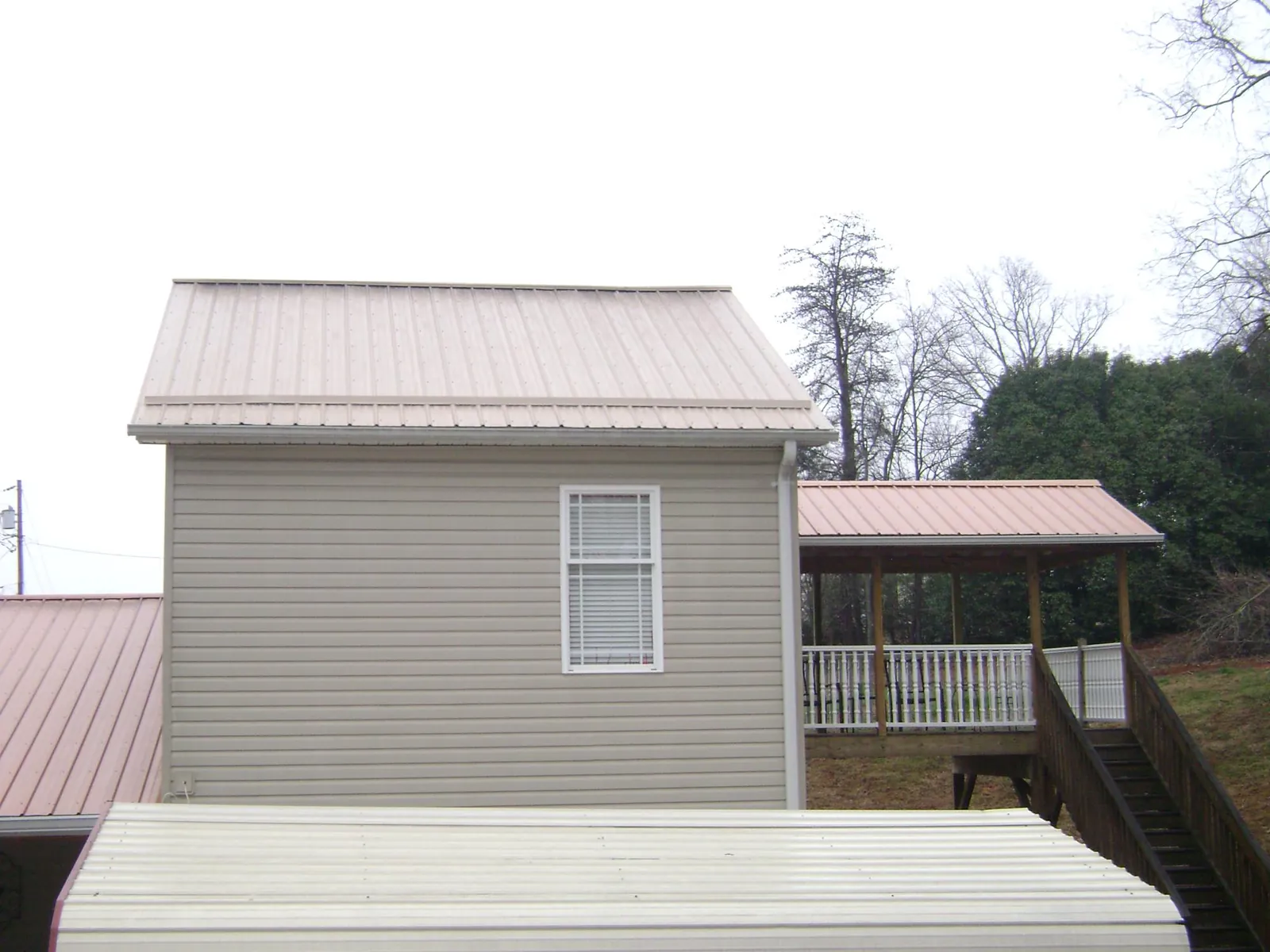 Tan metal roofs on a two story addition and attached porch, from a Roof Replacement job in Spring Gap