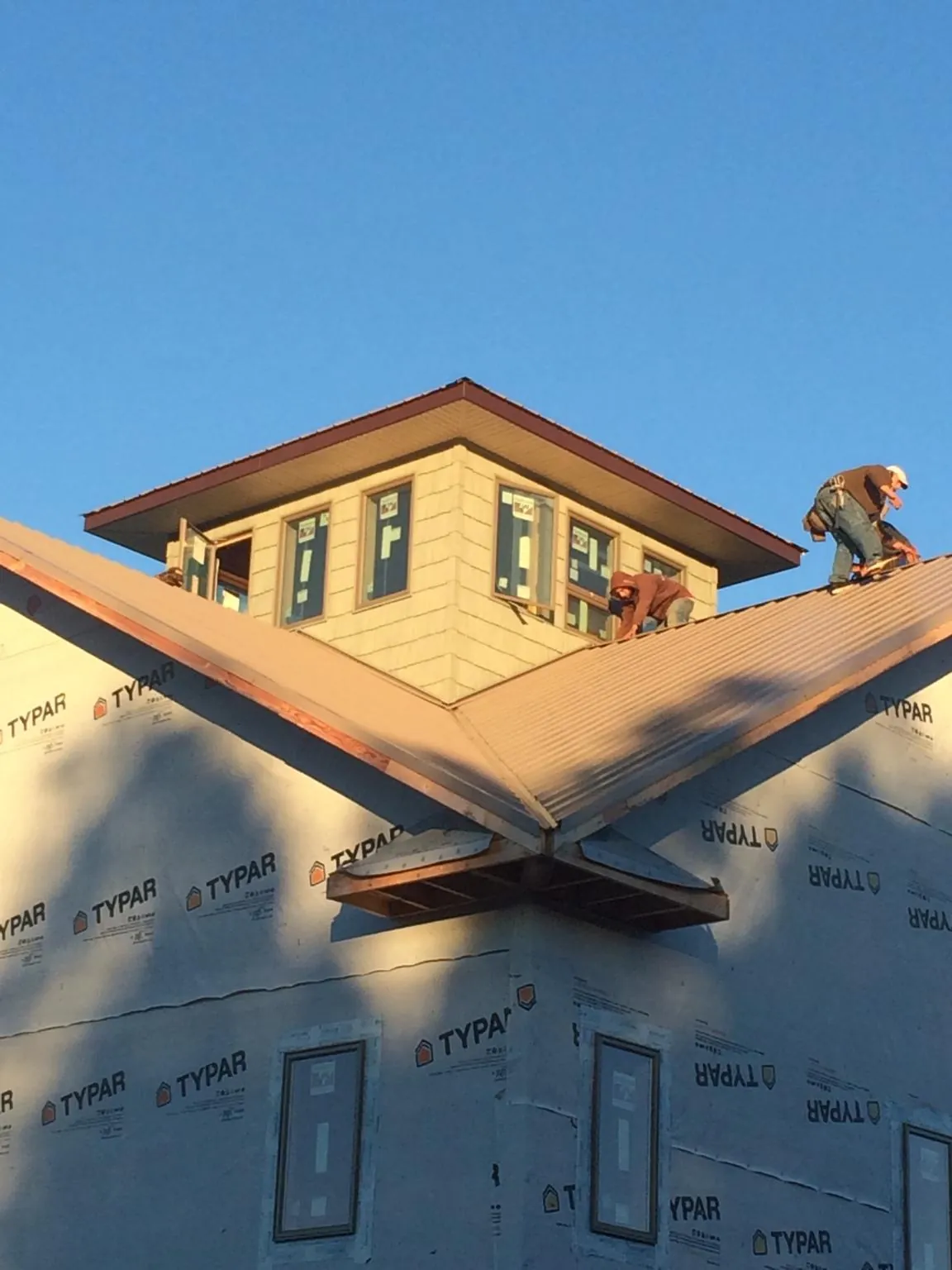 Roofers working around a rooftop cupola on a new metal roof at sunset — Roof Waterproofing in Spring Gap by Roofing Brothers